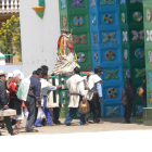 Procesión entra a la iglesia de San Juan Chamula con una litera, en la que varios hombres cargan a alguno de los santos del pueblo, ricamente ataviado a la manera tzoltzil.